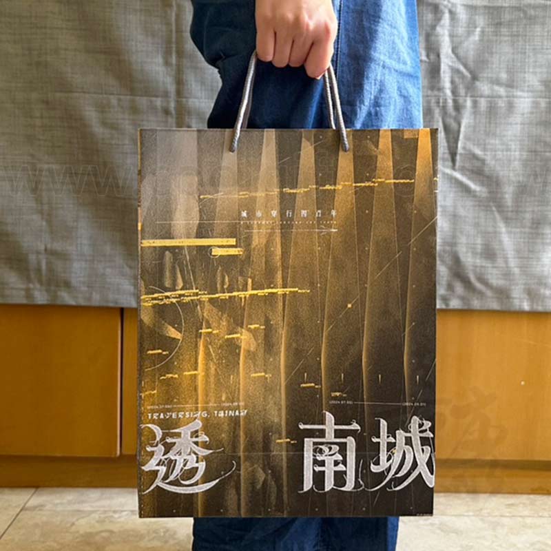 手持咖啡色紙袋，購物紙袋特寫「透 南城」文字
